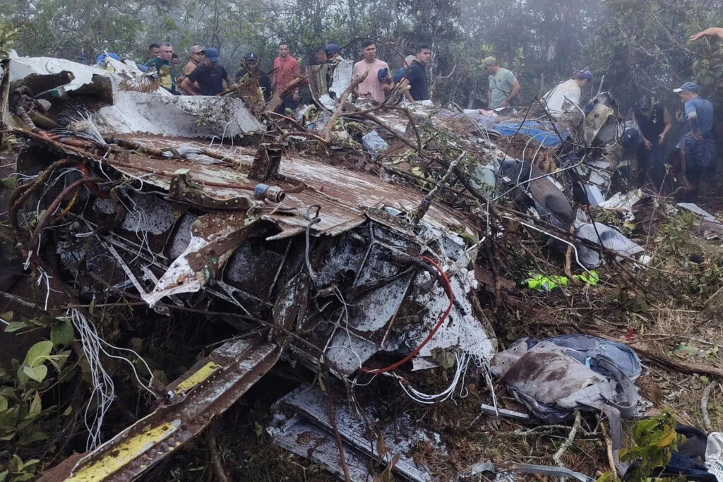 Des personnes se tiennent près de l'épave d'un avion qui s'est écrasé à Playa de Belén, dans le nord de Santander , en Colombie , le 28 janvier 2026. © Notiplaya/via REUTERS
